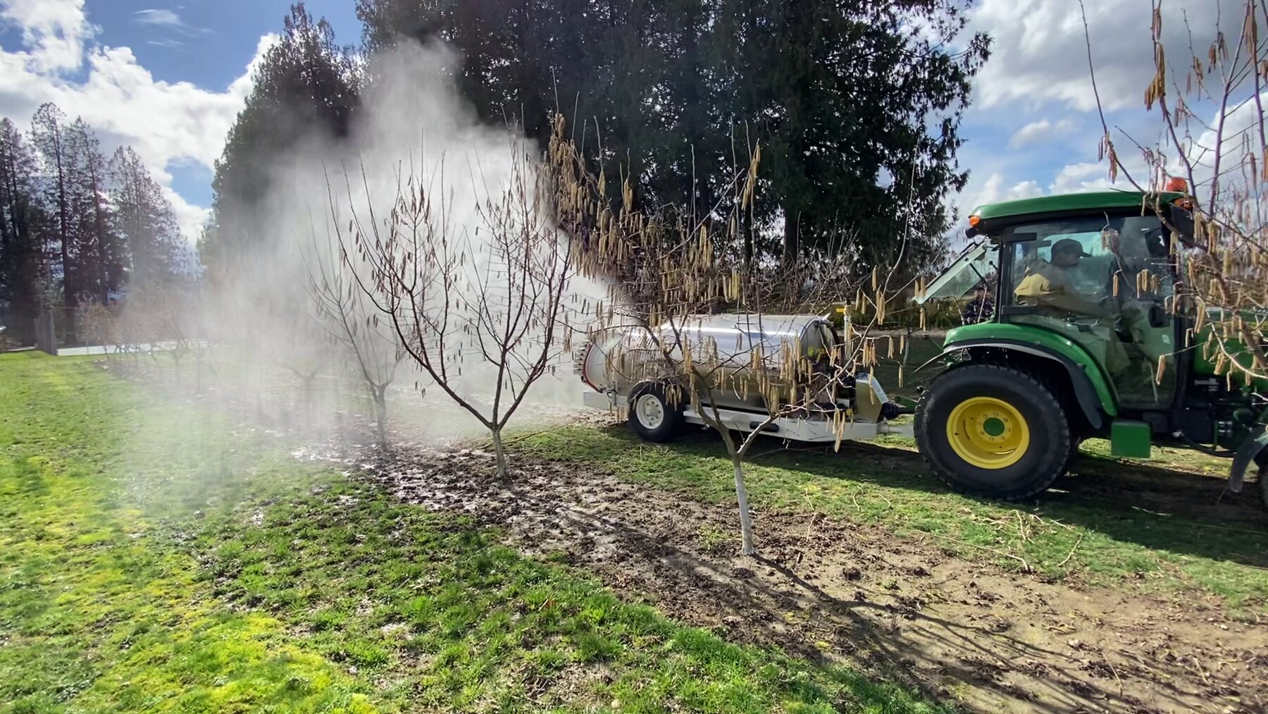 Automated orchard sprayer in the field, with sensor-controlled boom spraying trees